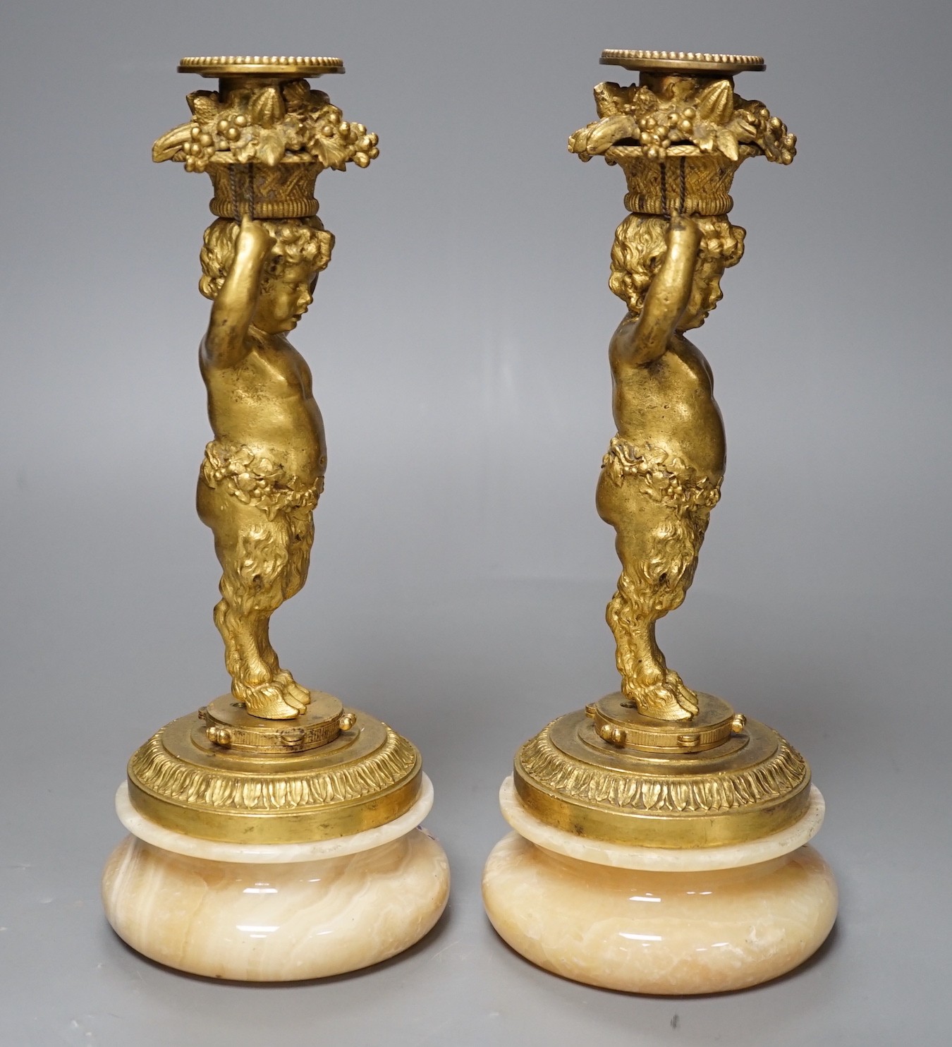 A pair of French gilt metal and onyx Bacchic faun candlesticks, 25.5 cms high